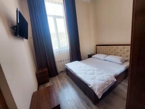 Habitación pequeña con cama y ventana en Samarabonu Hotel en Samarcanda