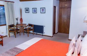 1 dormitorio con 1 cama, mesa y sillas en Koi Aiken en El Calafate