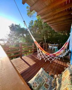 a hammock on a deck with a table and chairs at Double Deck - Linda vista com Jacuzzi in Palhoça