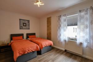 two beds with orange sheets in a bedroom with a window at Ferienwohnung Mitten im Pott in Bottrop