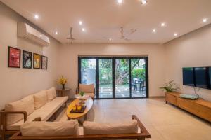 a living room with a couch and a tv at Castle Rock Villa By Tropicana Stays in Lonavala