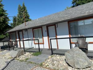 a house with a porch and a rock in front of it at Oceanside Villas in Sechelt