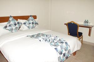 a bedroom with a bed and a table and a chair at Sai Inn Eldoret in Eldoret