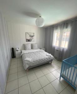 a white bedroom with a bed and a window at La Villa de l'Olivier piscine privée et parking in Carcassonne