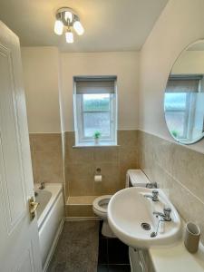 a bathroom with a sink and a toilet and a mirror at Modern 2 bedroom apartment near Glasgow Airport in Paisley