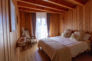a bedroom with a bed and a chair and a window at La Cabane du Petit Tour in Langogne