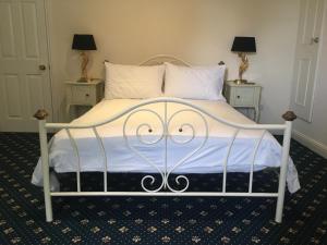 a bed with a metal frame and white sheets and pillows at Stay at The lodge set in the grounds of a beautiful Manor House in Wimborne Minster