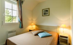 a bedroom with a bed with two lamps and a window at Lagrange Vacances Le Hameau De Peemor Pen in Crozon +13 photos