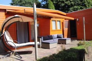 een patio met een bank en een parasol bij Veluwe Park Reewold Chalet Eclipse in Putten