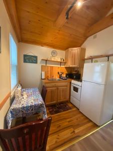 a kitchen with a table and a white refrigerator at Pine Grove Cottages in Lincolnville