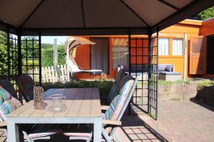 eine Terrasse mit einem Tisch und Stühlen unter einem Zelt in der Unterkunft Veluwe Park Reewold Chalet Eclipse in Putten