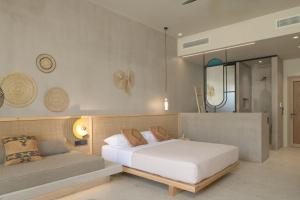 - une chambre avec un lit blanc et un canapé dans l'établissement NERĒA Boutique Hotel, à Plakias