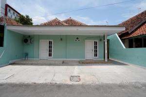 a green house with white doors in a parking lot at OYO 91389 Anggrek Residence Syariah in Lebakwangi