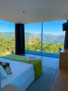 a bedroom with a large bed with a large window at Oak Nature in Vieira do Minho