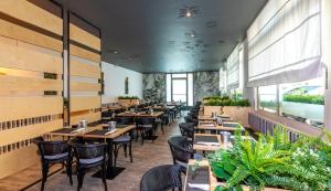 un ristorante con tavoli e sedie in legno e piante di Regina Urban Beach Hotel a Lido di Jesolo