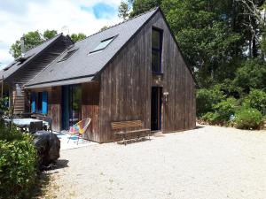 a large wooden building with a bench and a house at Plage700m, Maison d'hôte très calme,écrin de verdure, Sauna, Borne élect, Bord GR34 in Moëlan-sur-Mer