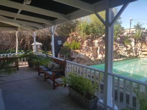 a porch with a bench and a swimming pool at Best Little Guest House new name is Beit Shalom Guest House in Oudtshoorn