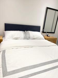 uma cama branca com uma cabeceira preta e um espelho em ANGIE HOME em Luton