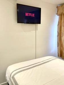 a flat screen tv on a wall next to a bed at ANGIE HOME in Luton