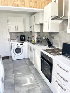 a kitchen with white cabinets and a washer and dryer at ANGIE HOME in Luton