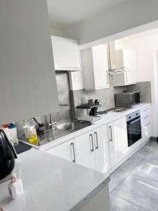 a kitchen with white cabinets and a sink at ANGIE HOME in Luton