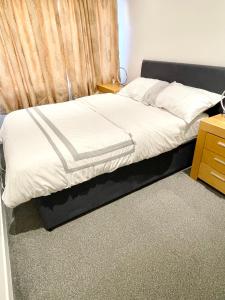 a bed with a black frame and white sheets at ANGIE HOME in Luton