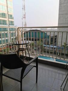 Un balcón con una silla y mesas en un edificio en Two Bedroom Apartment at el Royale Hotel, en Bandung