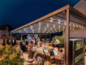 a group of people sitting at a table under a pergola at Apartments MUN Petrovac in Petrovac na Moru