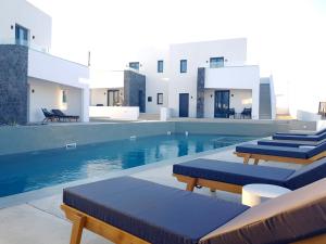 una piscina con sedie imbottite blu accanto a un edificio di myLithos Suites a Monolithos