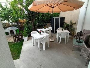 um pátio com mesas brancas e um guarda-chuva em La Fenice em Budoni