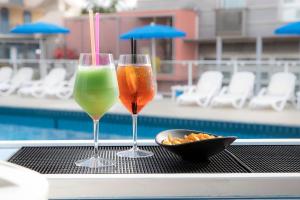 two wine glasses sitting on a table next to a pool at Hotel Rosanna 3 Stelle Superior in Lido di Jesolo