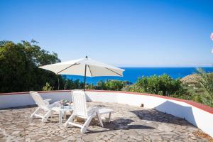 un patio con 2 sillas y una sombrilla en Villa Duca Country House, en Castellammare del Golfo