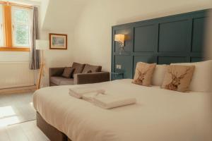 a bedroom with a large white bed with a green headboard at Ballinluig Rooms & Suites in Pitlochry