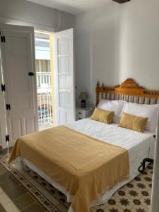 een slaapkamer met een groot bed met witte lakens en gele kussens bij La Casa de Lea in Béjar