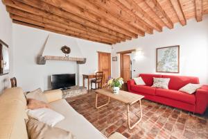 een woonkamer met een rode bank en een open haard bij Country house Viaro_150sqm in Vanzo