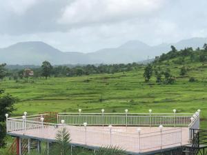 a white bridge with a view of a green field at Tamboo Resort Vajreshwari in Thane