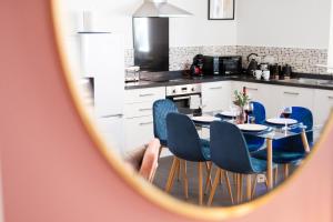 a kitchen with a table and blue chairs in it at Corinium Lodge - town centre apartment in Cirencester