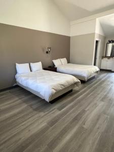 two beds in a room with wood floors at Captain's Lodge Motel in Gloucester