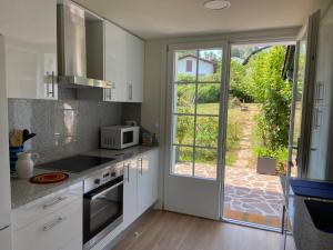 a kitchen with white cabinets and a large window at Saint Jean Pied de Port: Nere Nahia in Saint-Jean-Pied-de-Port