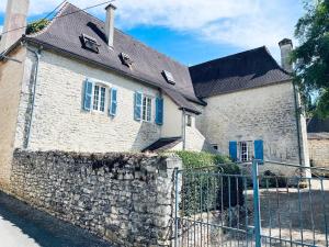 Lanzac的住宿－Auberge du lion d'or，一座带蓝色百叶窗和围栏的古老石头建筑