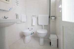 Baño blanco con aseo y lavamanos en Hostal Capri, en Es Pujols
