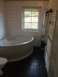 La salle de bains est pourvue d'une baignoire, d'une fenêtre et de toilettes. dans l'établissement Lønne Feriepark Holiday House 53, à Lønne Hede