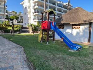 un parque infantil con un tobogán frente a un edificio en MI CAPRICHO, Beach Front Apartment P.14 3ºB, en Mijas Costa