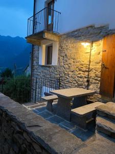 ein Steingebäude mit einem Picknicktisch und einem Balkon in der Unterkunft Casa Mille Sassi in Lionza