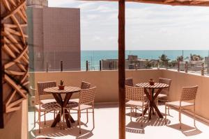 een patio met 2 tafels en stoelen op een balkon bij Conde Hotel in Maceió