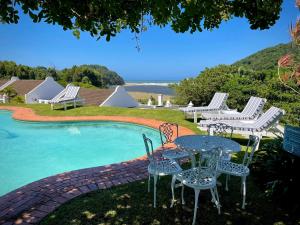 a group of chairs and tables next to a pool at Villa Songo, Estuary Country Estate, INVERTER & RENOVATED in Port Edward
