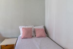 ein Bett mit rosa und weißen Kissen darauf in der Unterkunft Studio Flamant - Welkeys in La Rochelle