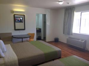 una camera d'albergo con letto, tavolo e finestra di American Inn a Hawthorne
