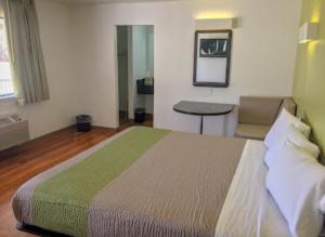 Un dormitorio con una cama, una mesa y un espejo. en American Inn, en Hawthorne 2 fotos más