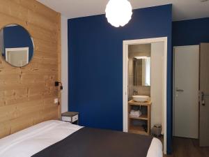 um quarto com uma parede azul, uma cama e um lavatório. em Le Relais d'Avajan em Avajan